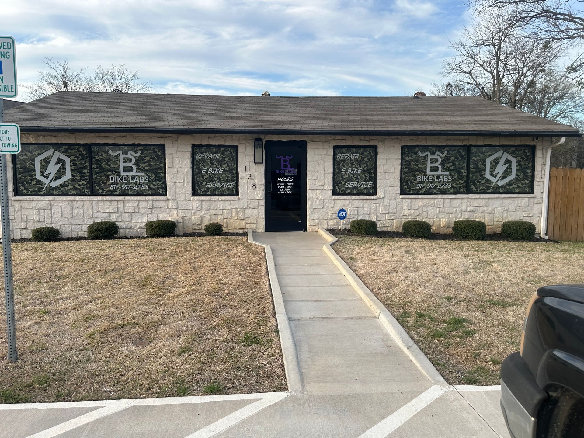 Brick storefront with a blue door, dark windows, and a concrete walkway in front