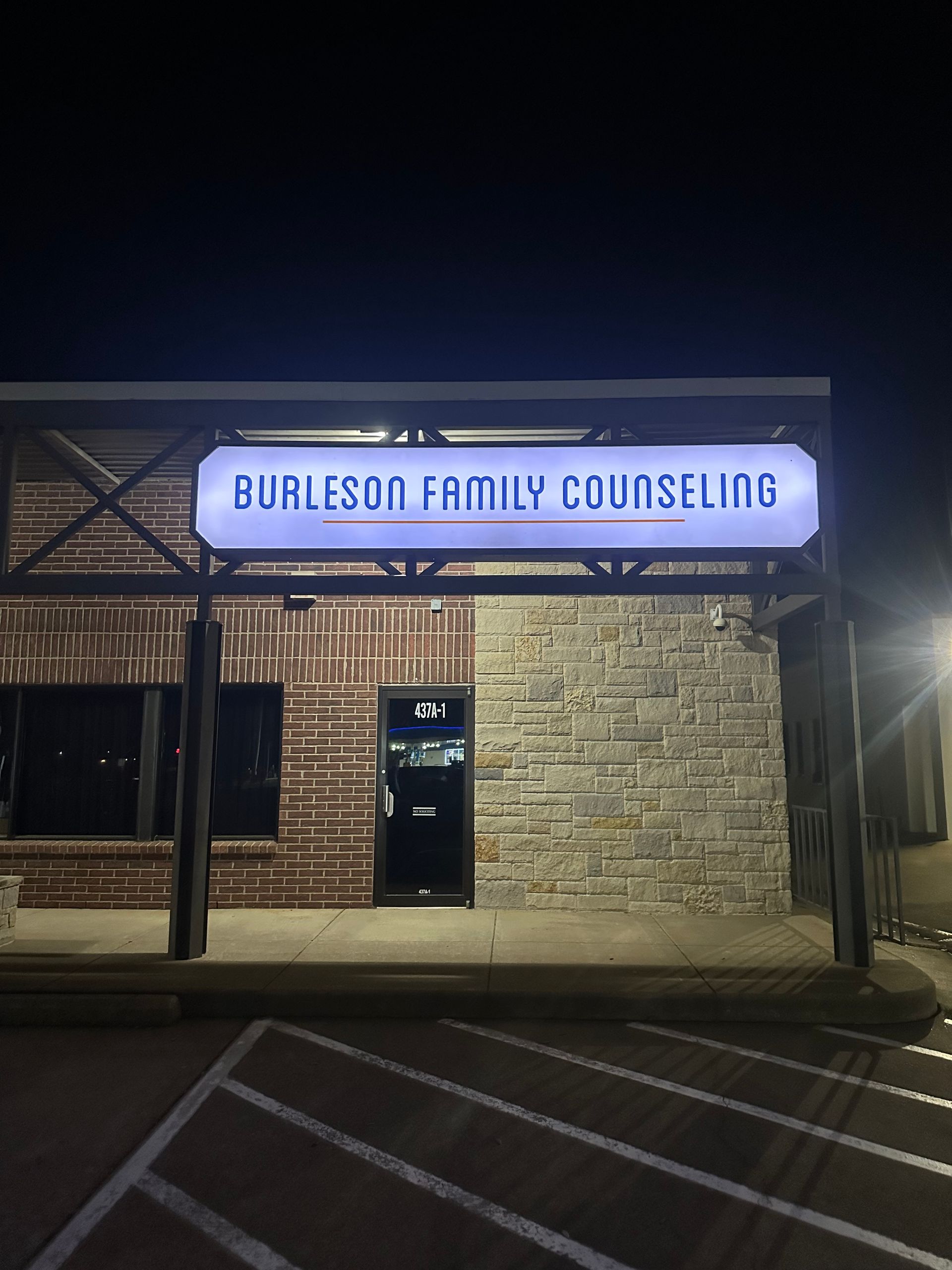 Burleson Family Counseling storefront at night, with lit sign and stone facade.