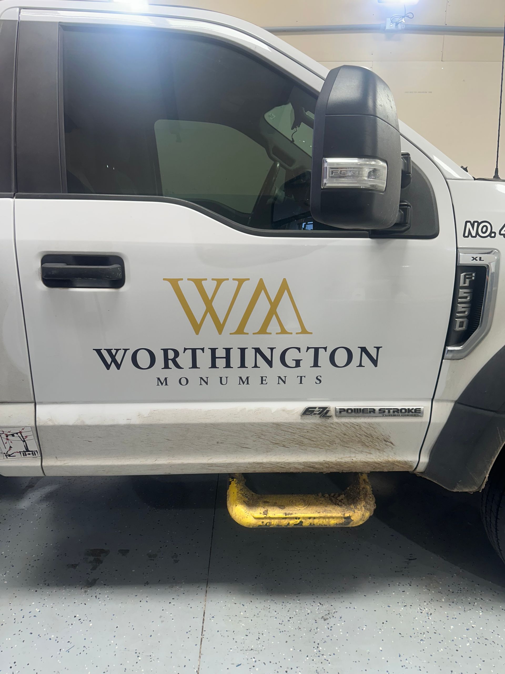 White Worthington van with gold logo parked over a yellow curb stop in a garage