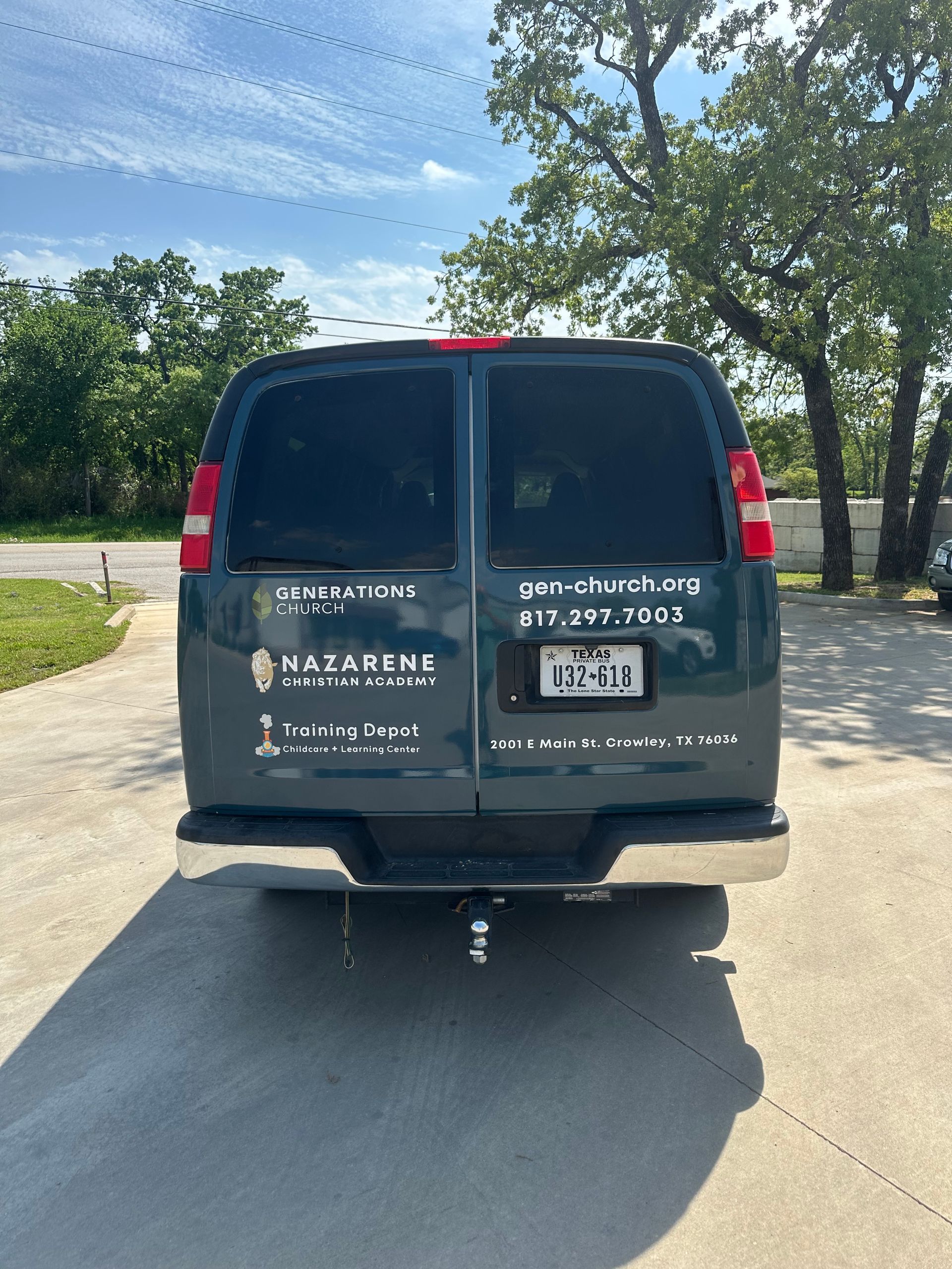 Black service van parked on a driveway, rear view with company lettering and phone number on the doors.