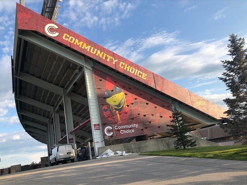 A low-angle view of the Community Choice Credit Union Convention Center stadium with a large red facade against a blue sky.