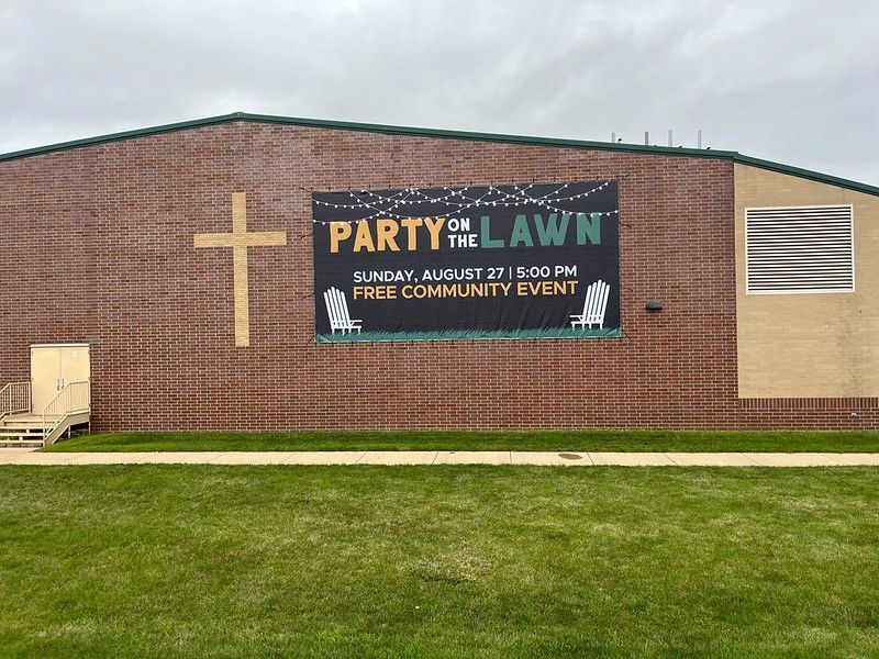 A brick building with a large wooden cross and a banner advertising a 