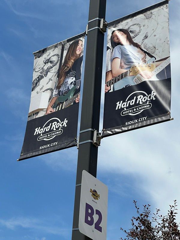 Two Hard Rock Hotel & Casino Sioux City banners featuring people playing guitars on a pole labeled with a B2 parking sign.