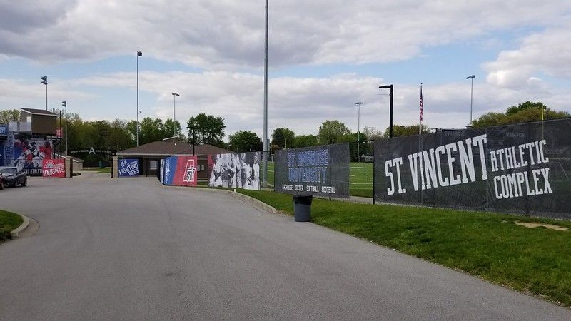 Entrance to the St. Vincent Athletic Complex with banners, signage, and light poles against a cloudy sky.