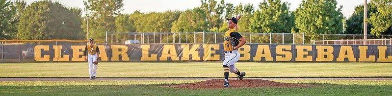 A baseball player pitching on a mound, with another player in the background in front of a 