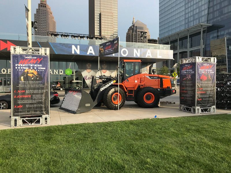 An orange front-loader parked between two promotional signs for 