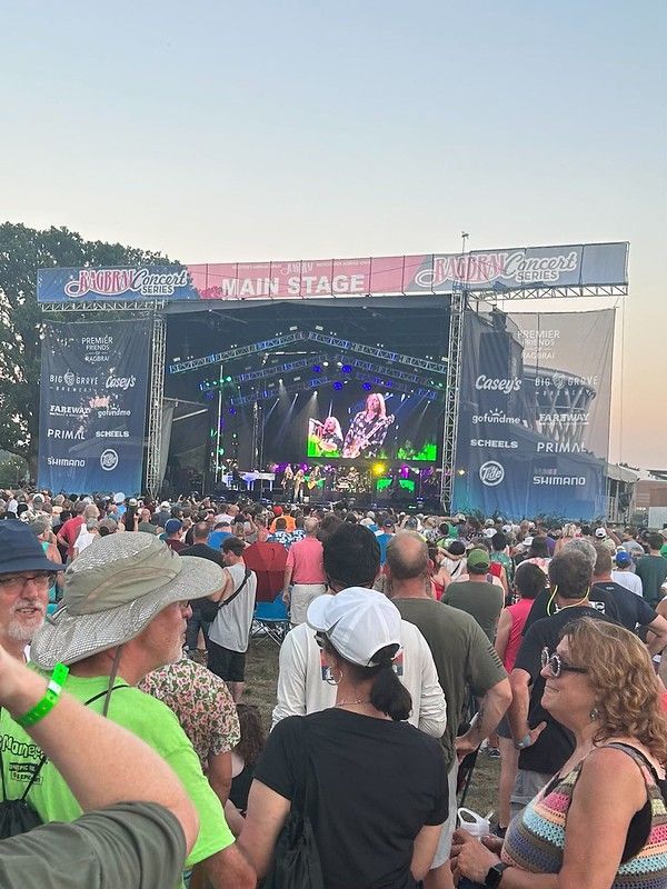 A crowd gathers before a large, lit outdoor concert stage during a sunset performance at the SunFest festival.