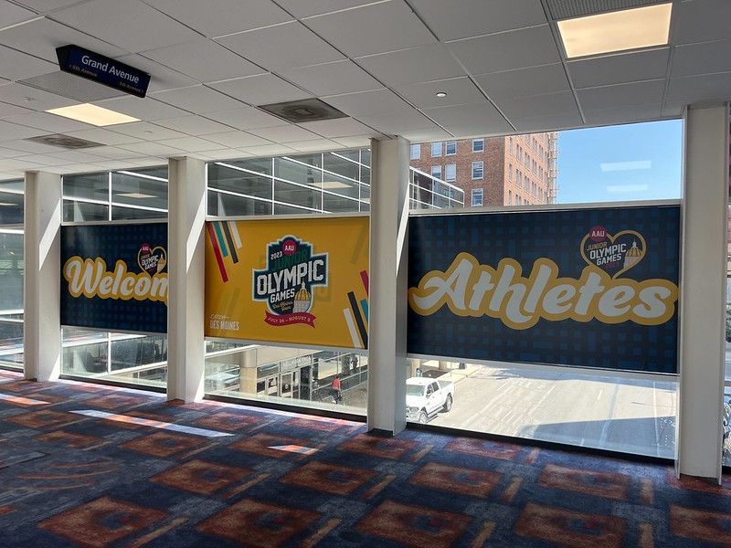 Three large banners hanging in a hallway window, reading 