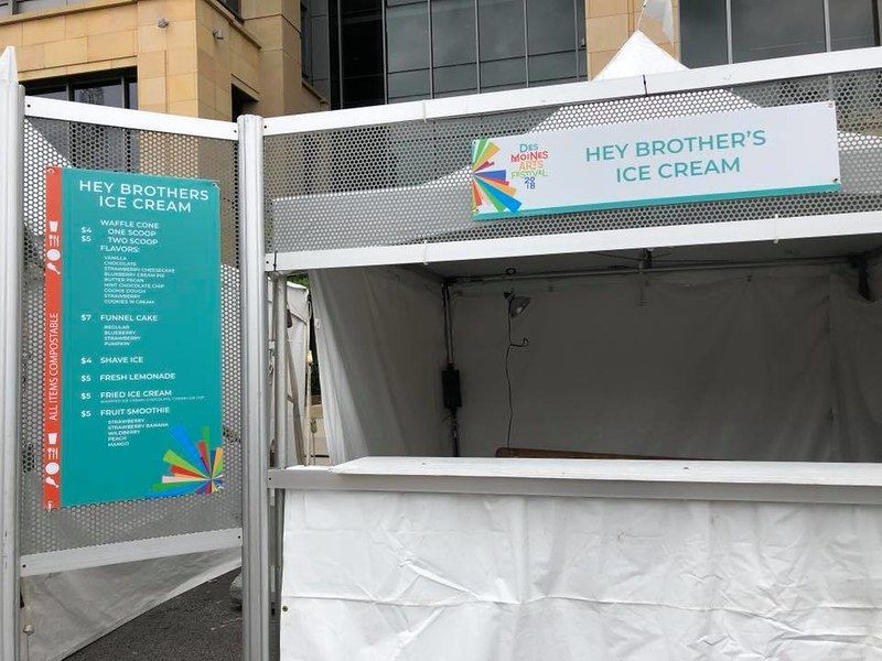 Hey Brother's Ice Cream stand featuring a teal menu sign on a white metal frame, set against an urban building exterior.