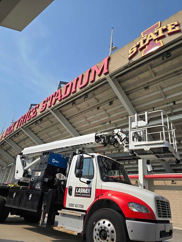A Lasher utility truck parked in front of the Jack Trice Stadium at Iowa State University on a sunny day.