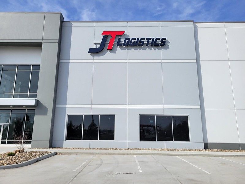 Exterior view of a gray industrial warehouse building with a prominent 