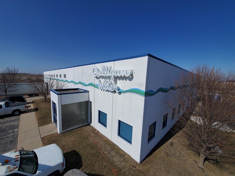 An angled view of a Milligan’s Water building with white walls, blue trim, a wave graphic, and a glass-block entryway.