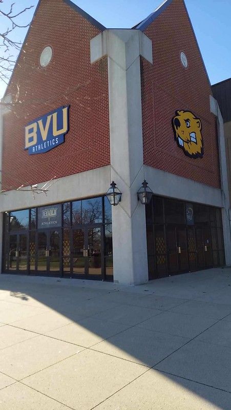 Brick building corner with a BVU Athletics sign and a beaver mascot logo on a sunny day.