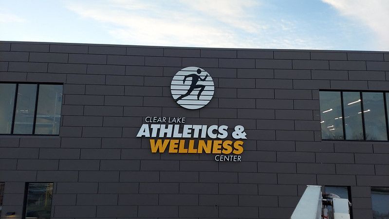 Exterior view of the Ocean State Athletics & Wellness Center with its logo and sign on a dark, tiled wall.