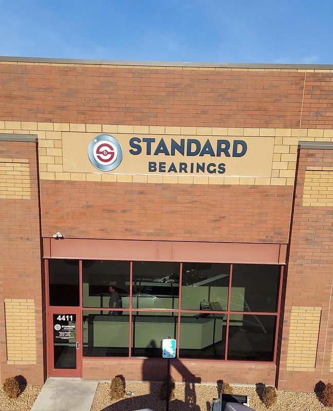 A storefront for Standard Bearings, featuring a brick exterior, tinted windows, and the company logo on a tan sign.