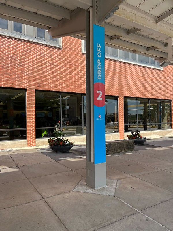 A blue sign on a pillar outside a red brick building marks 