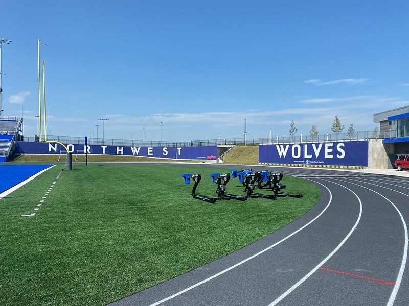 A blue running track and green field with “NORTHWEST WOLVES” signage on a sunny day.