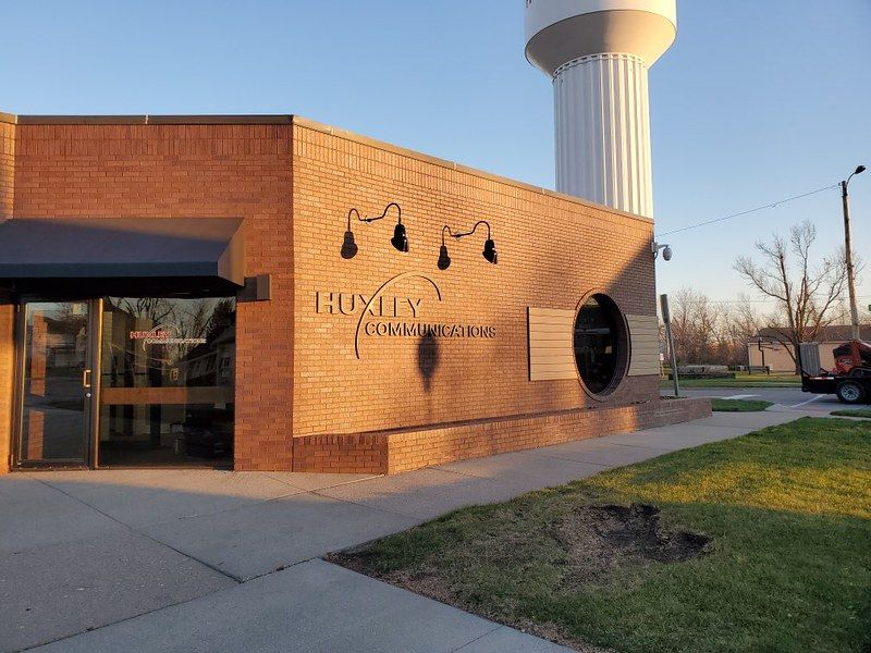 Brick facade of the Huxley Communications building with an entrance, circular window, and a water tower in the background.