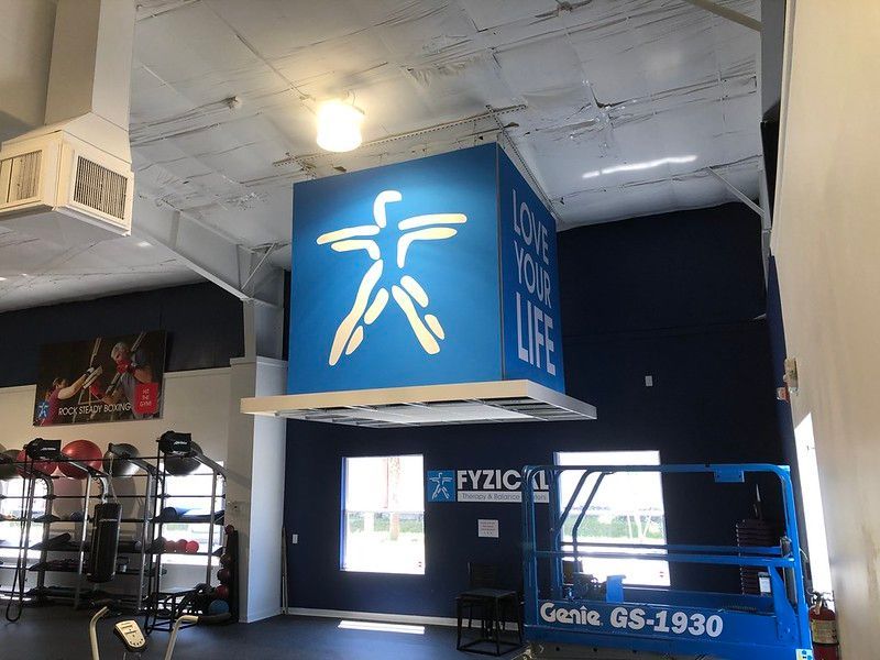 Interior of a Fyzical Therapy and Balance Centers facility, featuring a large blue, suspended cube with its logo and slogan.