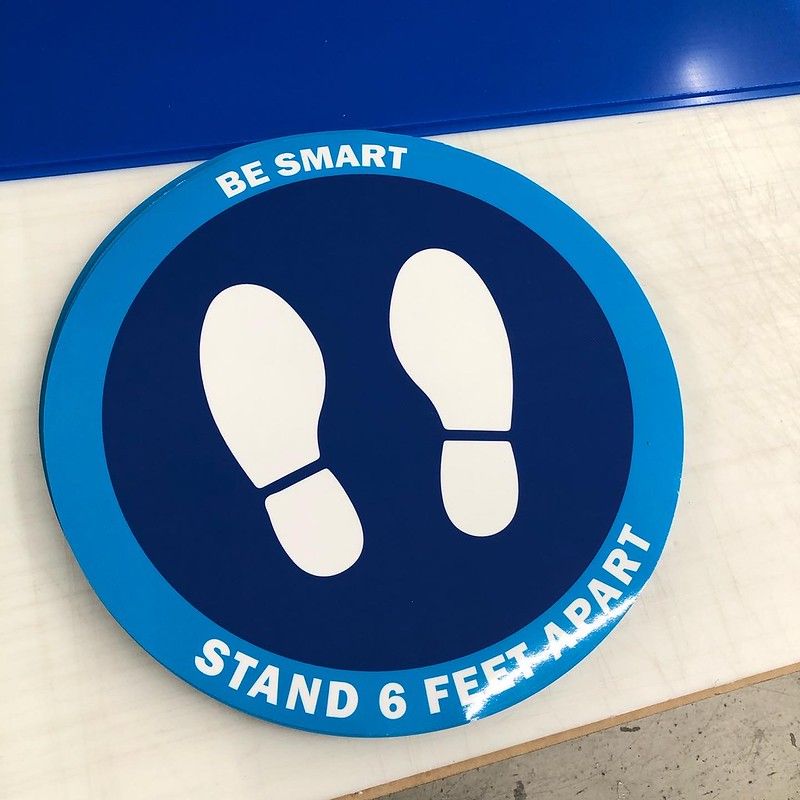 A blue, circular floor decal with two white footprints and text that reads, 
