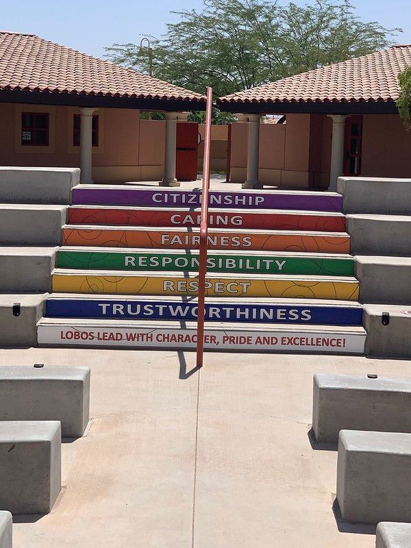 Outdoor concrete stairs painted with colorful bands labeled with values like Citizenship, Caring, and Trustworthiness.
