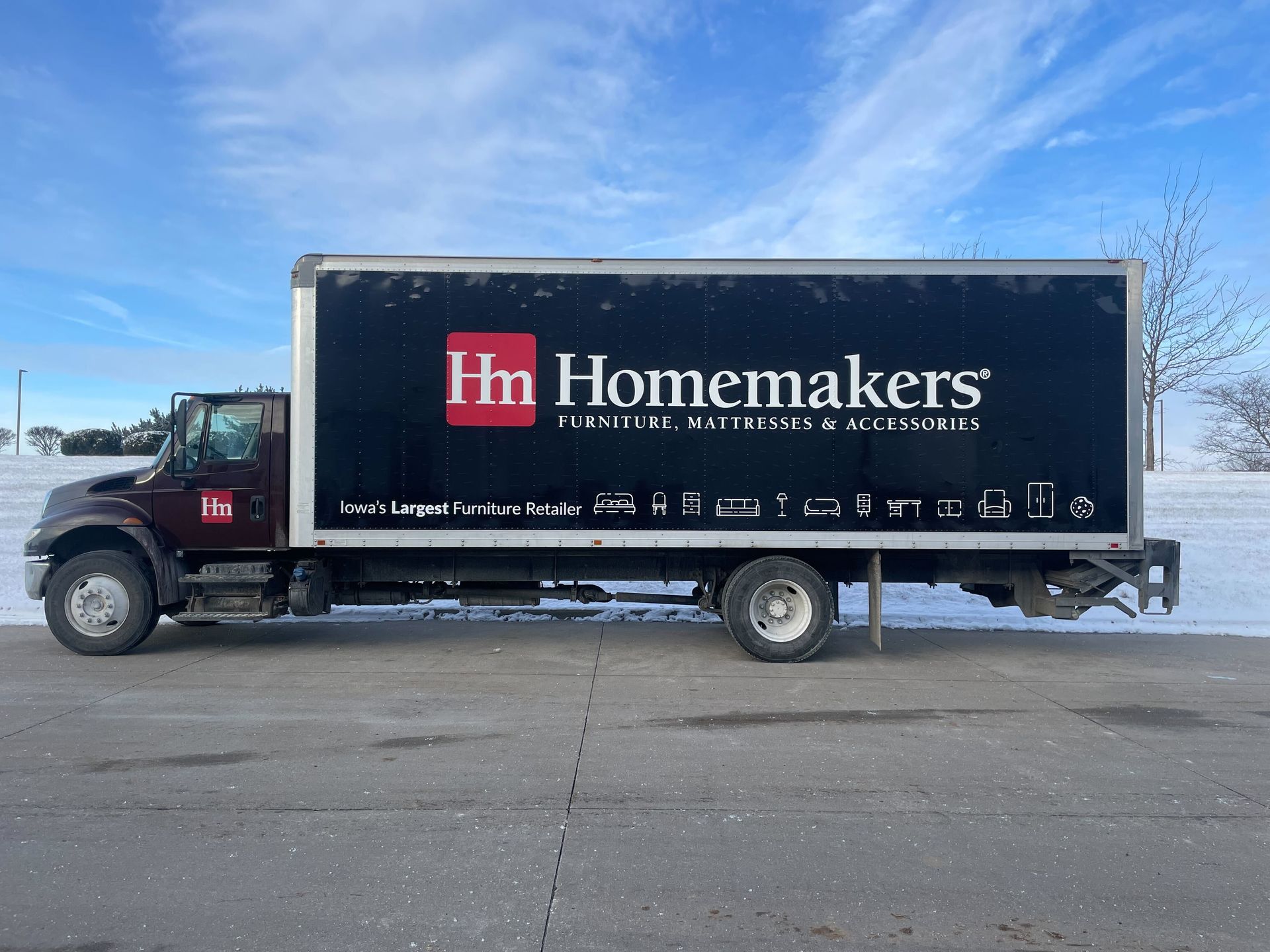 Homemakers moving truck parked on pavement under a blue sky.