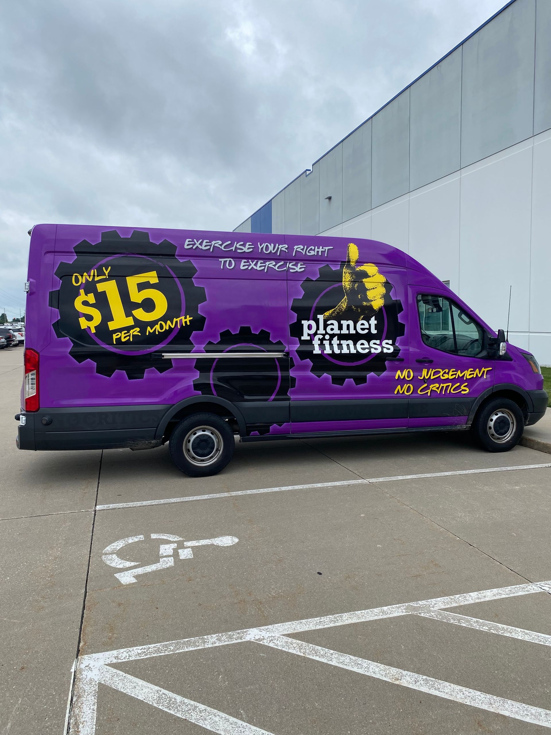 Purple Planet Fitness delivery van parked in a lot, with $15 promo graphic on the side.