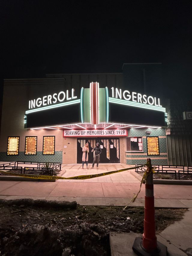 Neon-lit Ingersoll theater entrance at night, with a red cone and a banner above the doors.