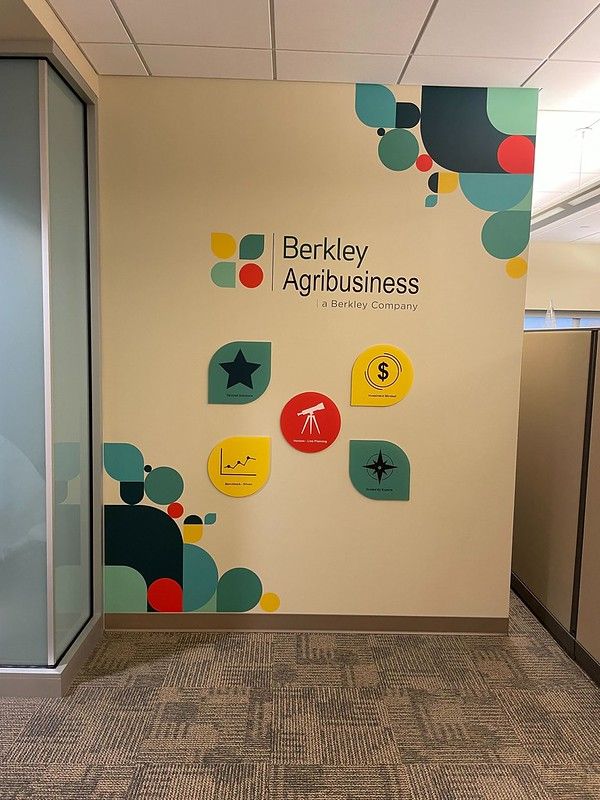 A Berkley Agribusiness office wall featuring a branded logo and colorful geometric icons in a modern workspace.