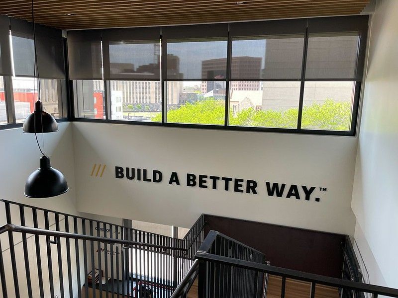 A staircase with modern railings leads toward a wall displaying the words, 