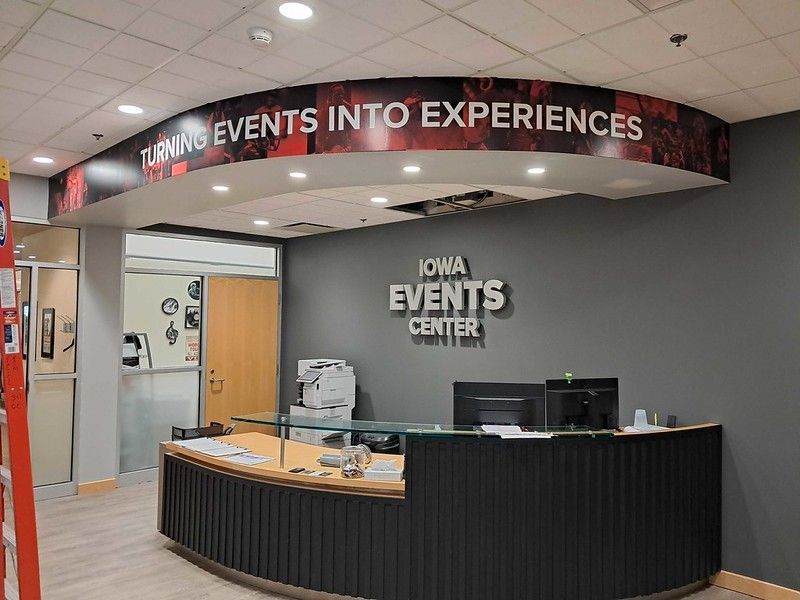 Reception desk at the Iowa Events Center with a dark gray wall, signage reading 