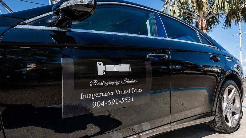 A black car featuring a promotional magnetic sign for Imagemaker Virtual Tours with the phone number 904-591-5531.