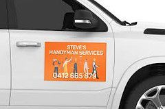 An orange rectangular car magnet on a white vehicle door reads 
