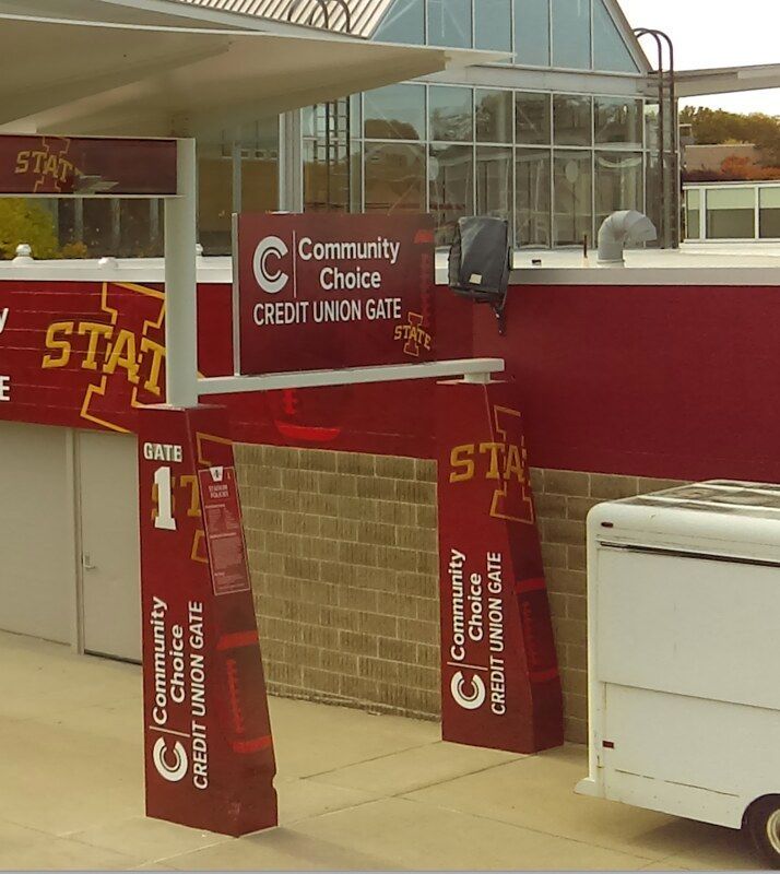Two maroon pillars and a sign marking the Community Choice Credit Union Gate at an Iowa State University stadium.
