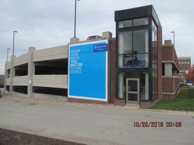 A concrete parking garage featuring a large blue banner that reads, 