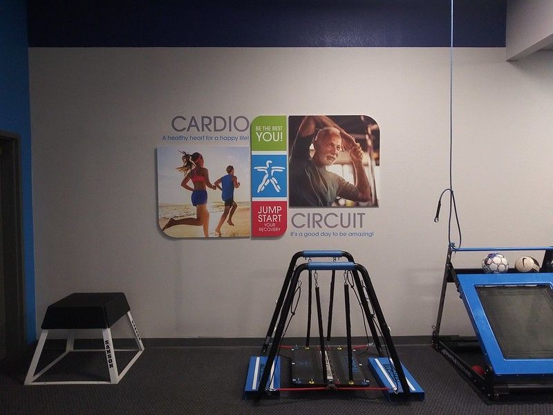 Gym room with exercise equipment, including a plyometric box and a circuit machine, below a Cardio Circuit wall sign.
