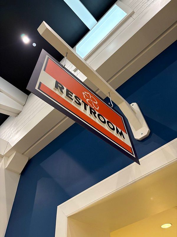 A hanging sign with a red background and white border that says 