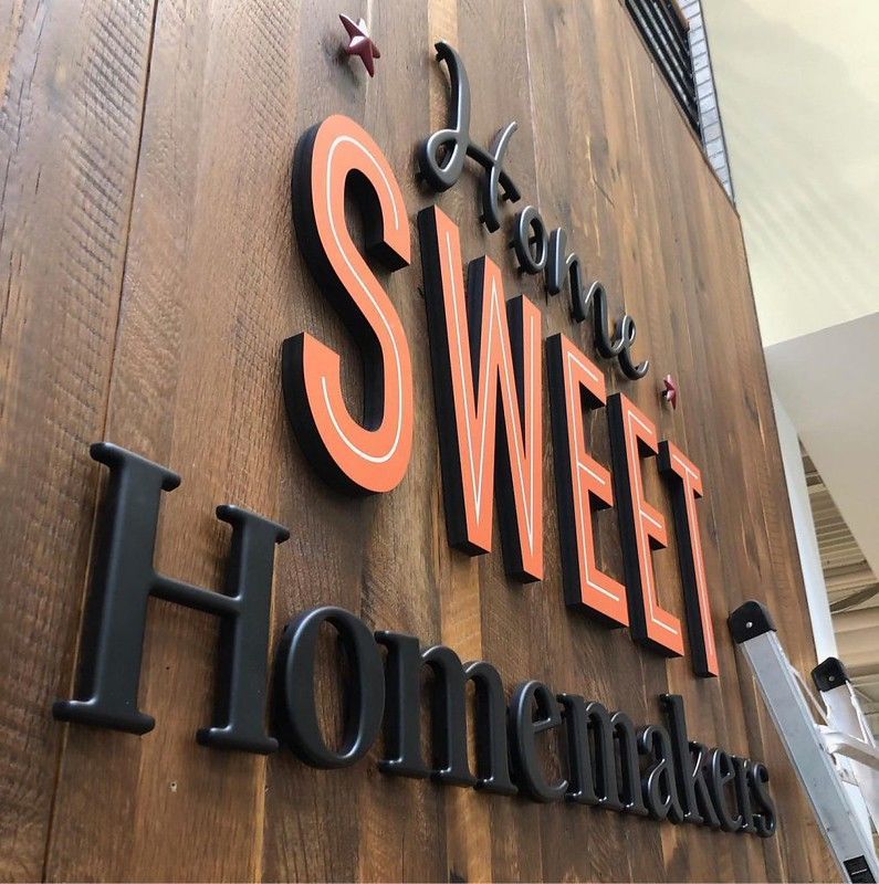 A wooden wall featuring 3D dimensional lettering that reads 