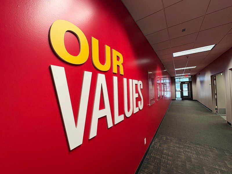 A red wall in a hallway features large, three-dimensional letters reading 