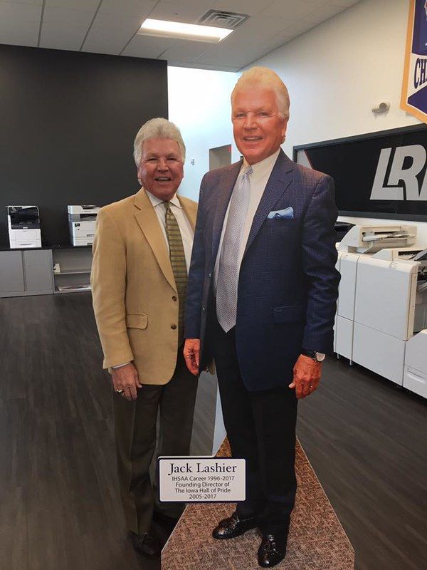 A person stands beside a life-sized cardboard cutout of Jack Lashier inside a print shop.