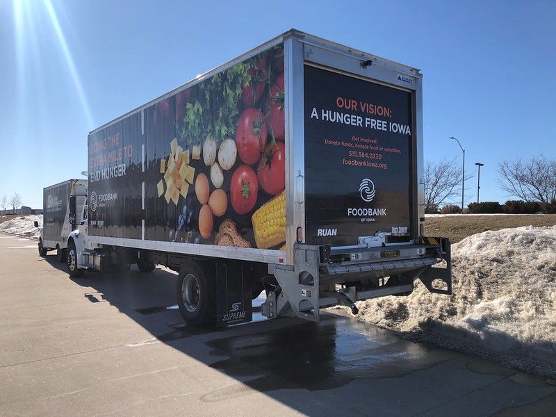 A food bank delivery truck parked on a road with snowbanks, featuring fresh produce graphics and a hunger-free mission.