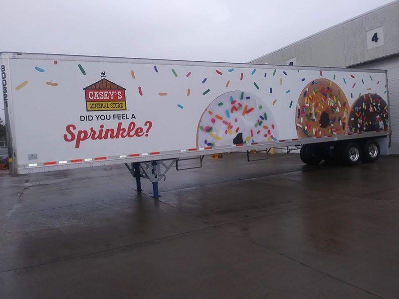 A side view of a white semi-trailer featuring the Casey’s logo, the text 