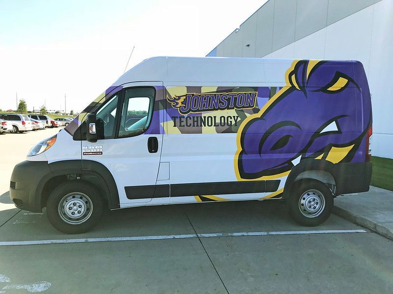 A white and purple wrapped van with a dragon mascot logo and 