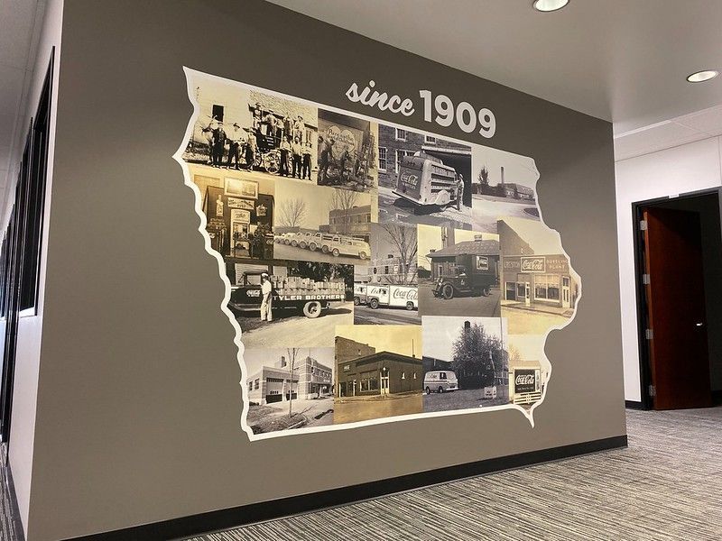 A wall mural shaped like Iowa, featuring black-and-white historical photos and the text 