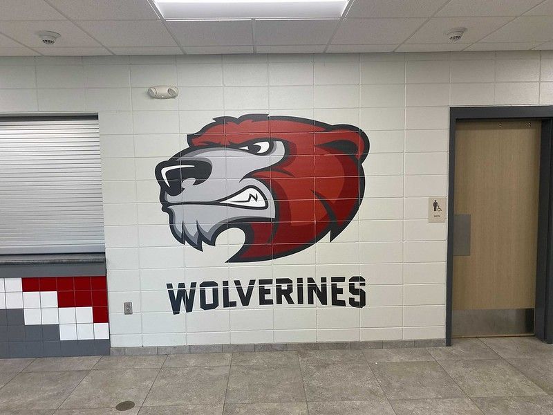 A mural of a red and grey wolverine mascot logo above the text 