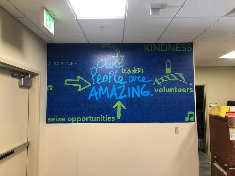 A blue wall mural with white and green text reading, 