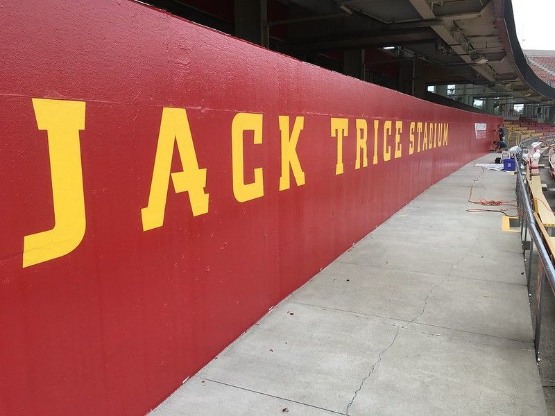 Red stadium wall with large, yellow painted lettering reading 