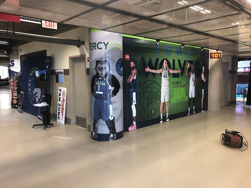 A pillar and wall in a stadium concourse featuring Minnesota Timberwolves graphics, players, and a mascot.