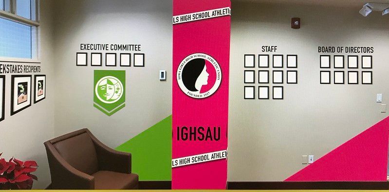 Office wall displays labeled for Executive Committee, Staff, and Board of Directors, with an IGSHAU pillar and photos.