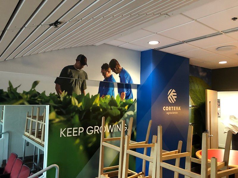 Three people stand on a platform installing large 